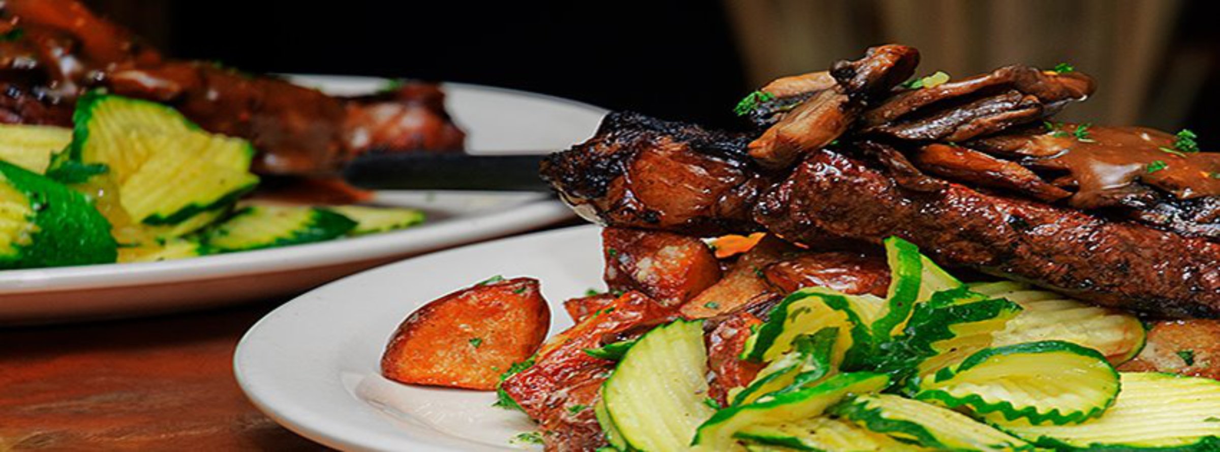 Plated steak dinner with grilled vegetables at Barney Prine's
