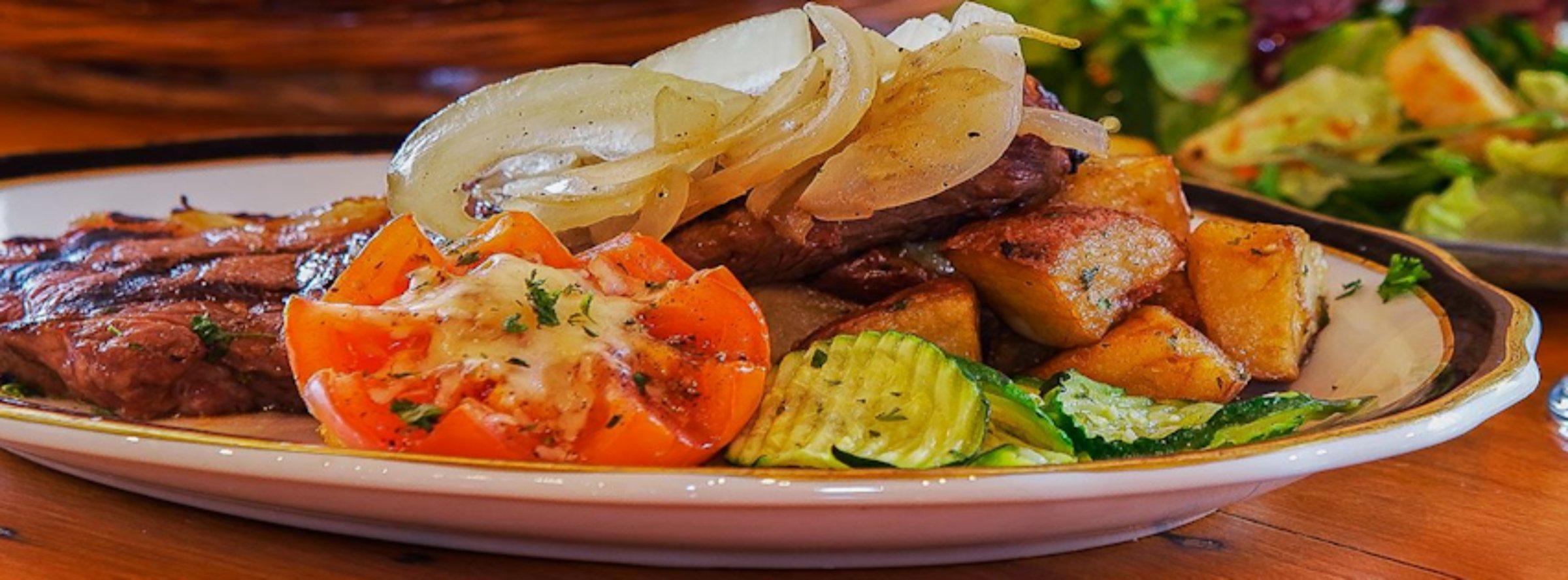 Steak dinner with tomato, onion, and roasted potatoes at Barney Prine's